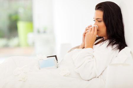 Erkältete Frau im Bett mit Schnupfen